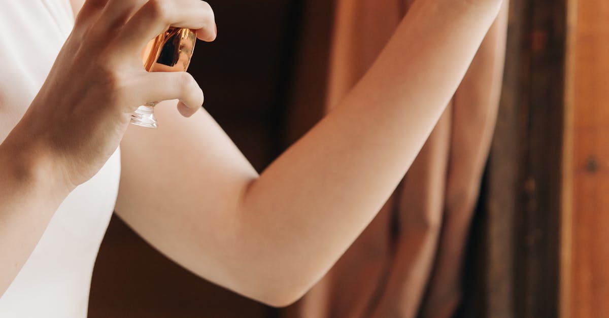 A woman in a white dress applying perfume indoors, highlighting luxury and elegance.